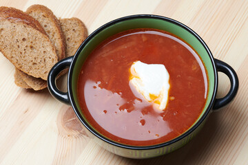 with sour cream borscht in a green plate and bread