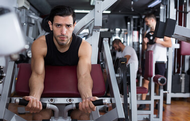 Fototapeta na wymiar Portrait of athletic man during workout with power exercise machine in gym club