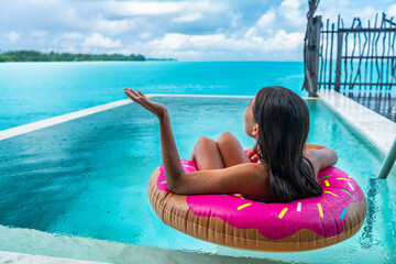 Rain vacation luxury swimming pool hotel resort. Ruined summer holidays tropical storm. Travel cancellation insurance. Sad funny woman crying on bad holiday floating in swim float donut