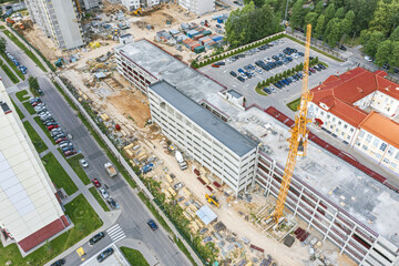 panoramic aerial view of working crane at construction site. multistory parking garage under construction.
