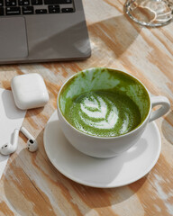 Morning, hygge and breakfast concept. Cup of Matcha latte, espresso, laptop and earphones on a wooden table. Top view