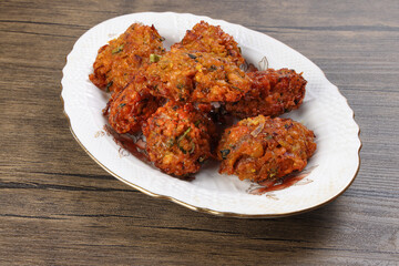 Fototapeta premium Deep fried piaju onion fitter bhajia on decorated ceramic plate over rustic wooden background