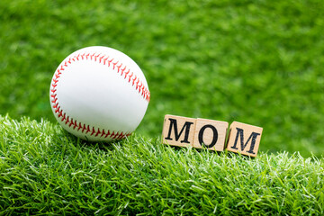 Baseball with word Mom for Mother's Day are on green grass
