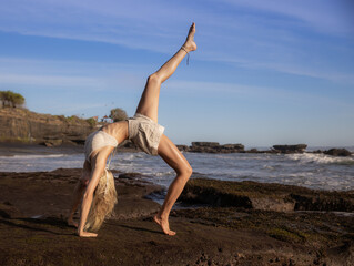 Outdoor yoga. Young woman practicing Eka Pada Chakrasana, One Legged Wheel Pose. Upward facing bow pose is a deep backbend. Flexible, fit body. Yoga retreat. Beach in Bali, Indonesia