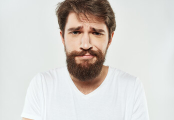 Obraz premium Bearded man in a white T-shirt on a light background sad face emotions beard