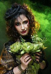 beautiful woman with bright creative make up holding dry flowers over black background