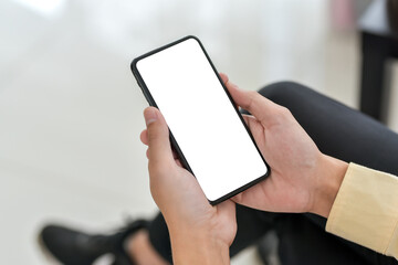 Close up businessman hand holding a smartphone blank white screen in the office. Mock up.