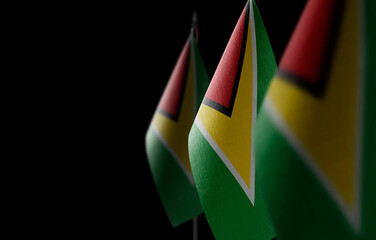 Small national flags of the Guyana on a black background