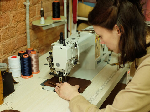 young woman sewing leather handbag
