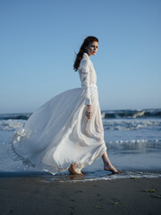 Fototapeta na wymiar Charming woman in a sundress near the ocean on the shore of the beach model red hair