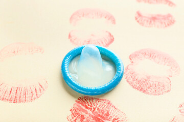 Lips prints with condom on color background. Erotic concept