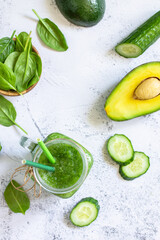 Green smoothie recipe. Healthy diet and nutrition, vegan and alkaline drinks. Fresh smoothie with cucumber, avocado and spinach on a gray stone. Top view. Flat lay. Copy space.