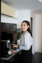 Portrait of happy young woman office worker making coffee from coffee machine in the office.