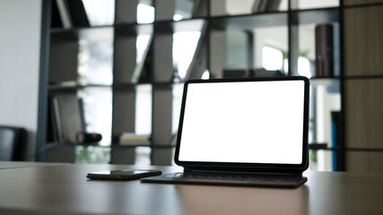 Mock up computer tablet with blank screen and smart phone on white office desk.