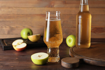 Bottle and glass with apple cider on wooden background