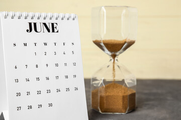 Flip paper calendar with hourglass on table