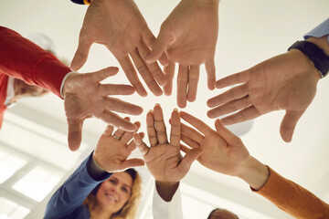 Close up view from below of a group of people folding their arms to each other symbolizing their unity and support. Team of people who are ready for fruitful work and a positive result.
