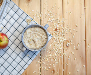 Fresh oatmeal porridge in a plate on a beautiful napkin and on a wooden table. A fresh and healthy breakfast.