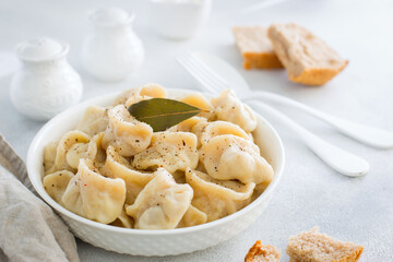 Handmade dumplings with meat on a white table, traditional Russian cuisine, horizontal