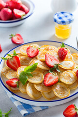 mini pancakes in a white plate with fresh strawberries, selective focus