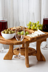 Serving wooden table for wine, glasses and snacks. Handmade segmented Portion wooden table. Grapes, cheese, wine and nuts.  