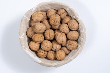 basket with whole walnuts on a white background, top view