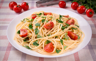Pasta spaghetti with cherry tomatoes and parsley on a light background.