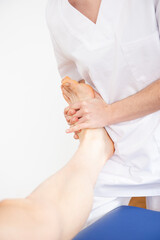 Closeup view of a physiotherapist treating the foot and ankle mobility of a patient.