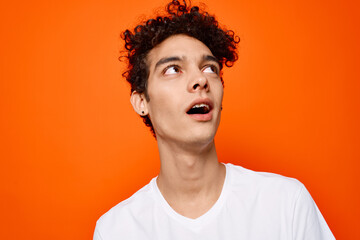 Cheerful guy in a white t-shirt emotion close-up orange background