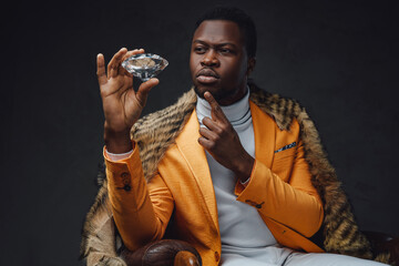 Pensive black man with fur holding diamond