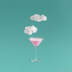 Minimal summer dream concept with martini glass pink cocktail drink and dreamy clouds on teal  green background. Fashion, party, dreaming creative idea.