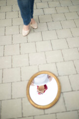 Naklejka premium Frau mit Brille und rosa Haaren spiegelt sich kreativ im runden Spiegel