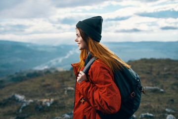 woman travels in the mountains landscape backpack red jacket and hat model