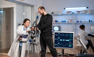 Team of medial researchers monitoring vo2 of man performance sports wearing mask running. Lab science doctor measuring endurance of sportsman while ekg scan runs on computer screen in laboratory.