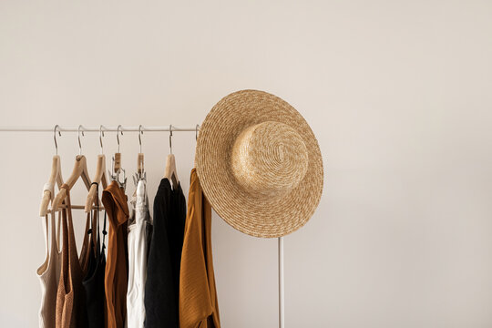 Women's fashion bright pastel clothes on clothing rack on white background. Minimalist fashion blog concept.