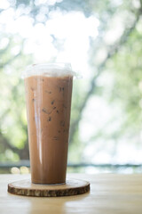 Iced coffee Mocha in tall plastic glass against nature background