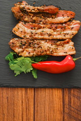 Raw Asian style marinated pork belly slices with red pepper and coriander on black stone board. Meat with herbs and spices. Meat industry product.