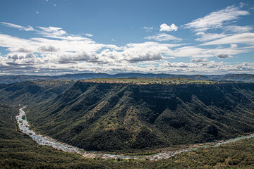 Fototapeta premium Meandering River Flowing Through Steep Tree-Lined Valley