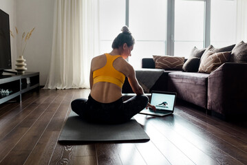 Woman doing online yoga at home. Female trener teaches asana in video conference. Health care, authenticity, sense of balance and calmness.
