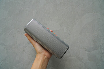 close up people hold Bluetooth speaker in hand for music connection with loft wall background