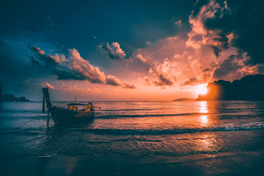 Amazing sunset with longtail boats silhouette at Railay beach, Thailand.