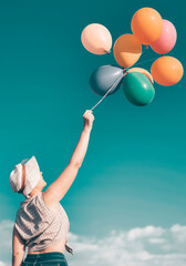 Woman with hat holdin balloons over summer sky