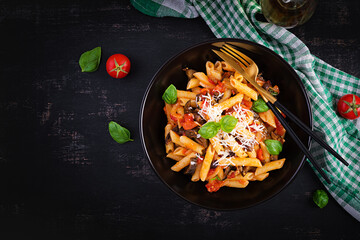 Pasta penne with eggplant. Pasta alla norma - traditional Italian food with eggplant, tomato, ricotta cheese and basil. Top view, overhead, copy space
