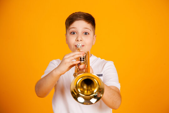 A boy plays the trumpet. Beautiful teenager boy plays trumpet musical instrument