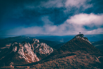 Fototapeta premium Man standing on top of cliff in summer mountains