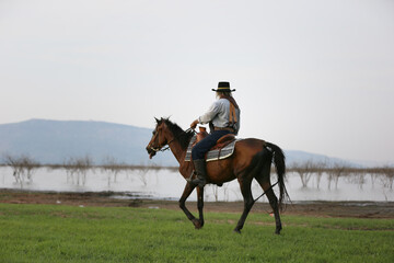 cowboy on horseback against a beautiful sunset, cowboy and horse at first light,mountain, river and...