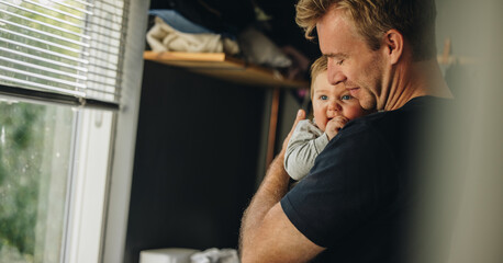 Father consoling his baby at home - obrazy, fototapety, plakaty