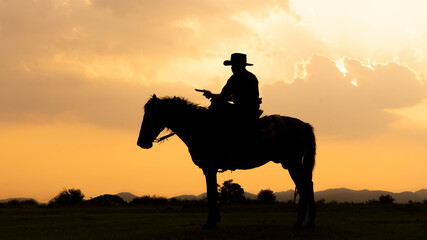 Silhouette Cowboy on horseback against a beautiful sunset, cowboy and horse at first...