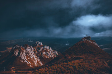 Fototapeta premium Man standing on top of cliff in summer mountains