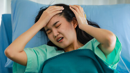 npatient female lying on a hospital bed, having a terrible painful headache, or migraine, placing...